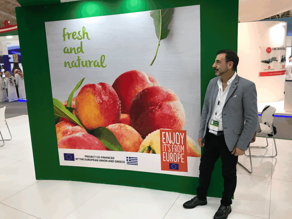 EU co funded promotional stand for European fresh peaches at Saudi Agriculture Exhibition 2017, with a representative standing next to the main branding panel.