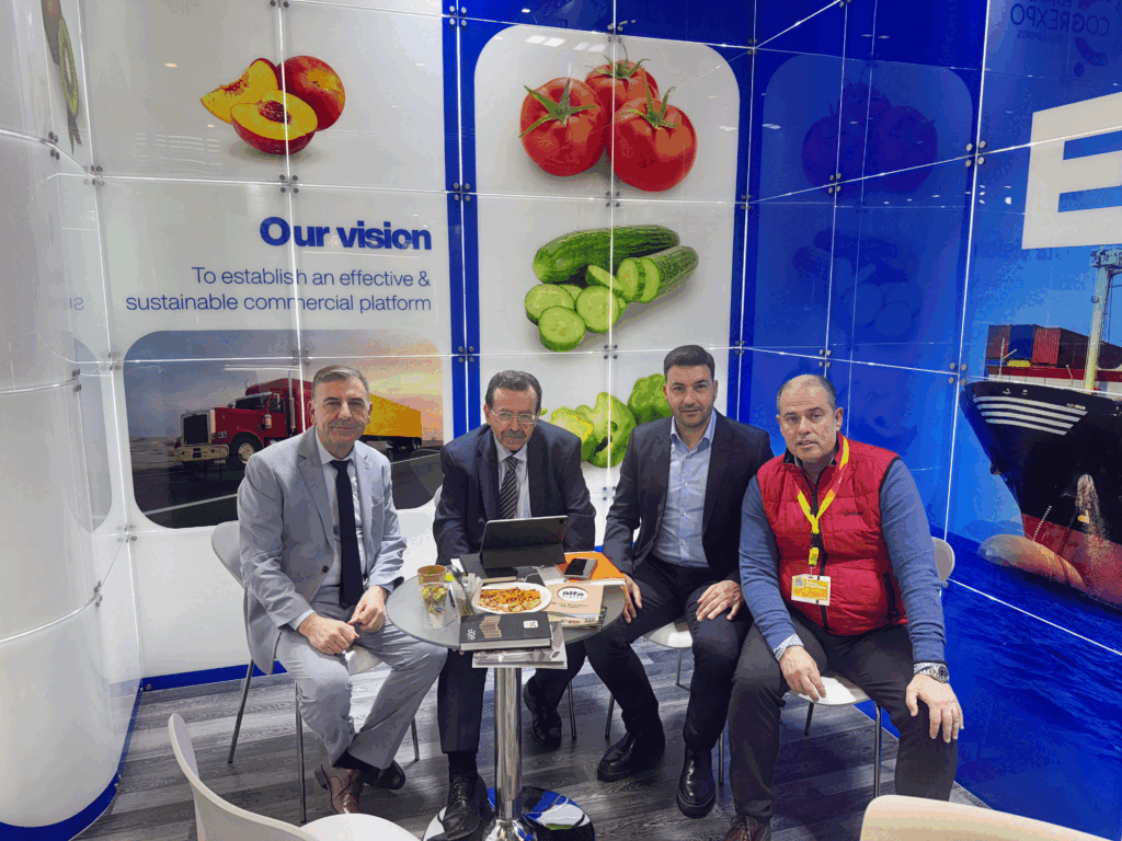 Business meeting at the booth during Fruit Logistica, with representatives seated in front of the cooperative’s visual branding.