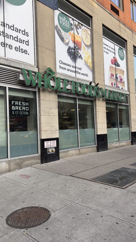 Exterior view of Whole Foods Market in New York City during a market visit to observe retail placements of European and Greek food products.