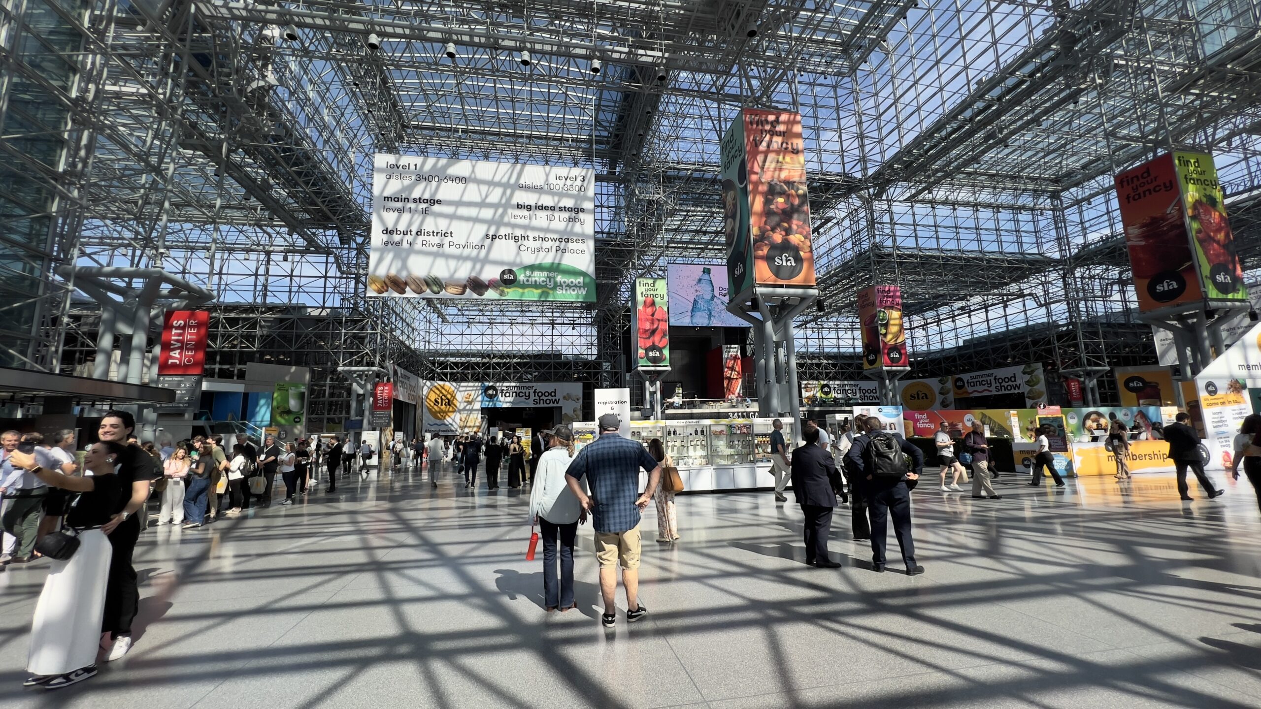 Interior of Javits Center during Summer Fancy Food Show 2025 with visitors walking through the main exhibition hall.