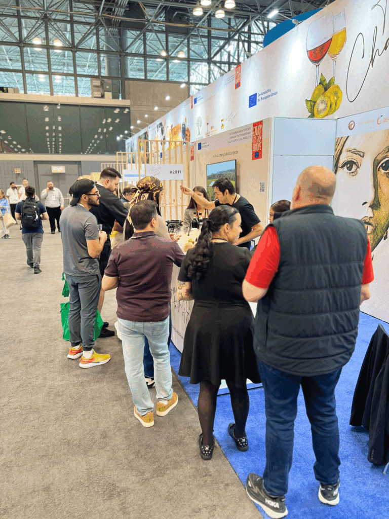 Visitors gathering at the European pavilion during the Summer Fancy Food Show in New York, attending tastings and learning about Mediterranean products.